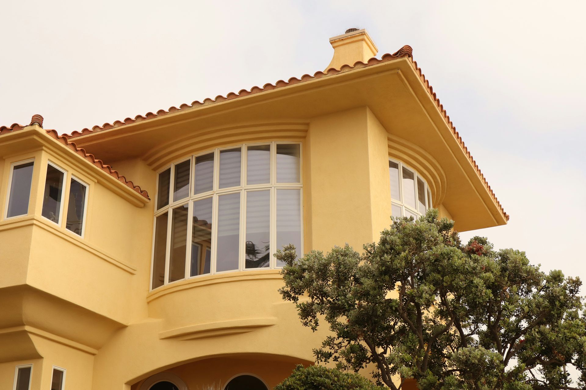 A yellow house with a tree in front of it