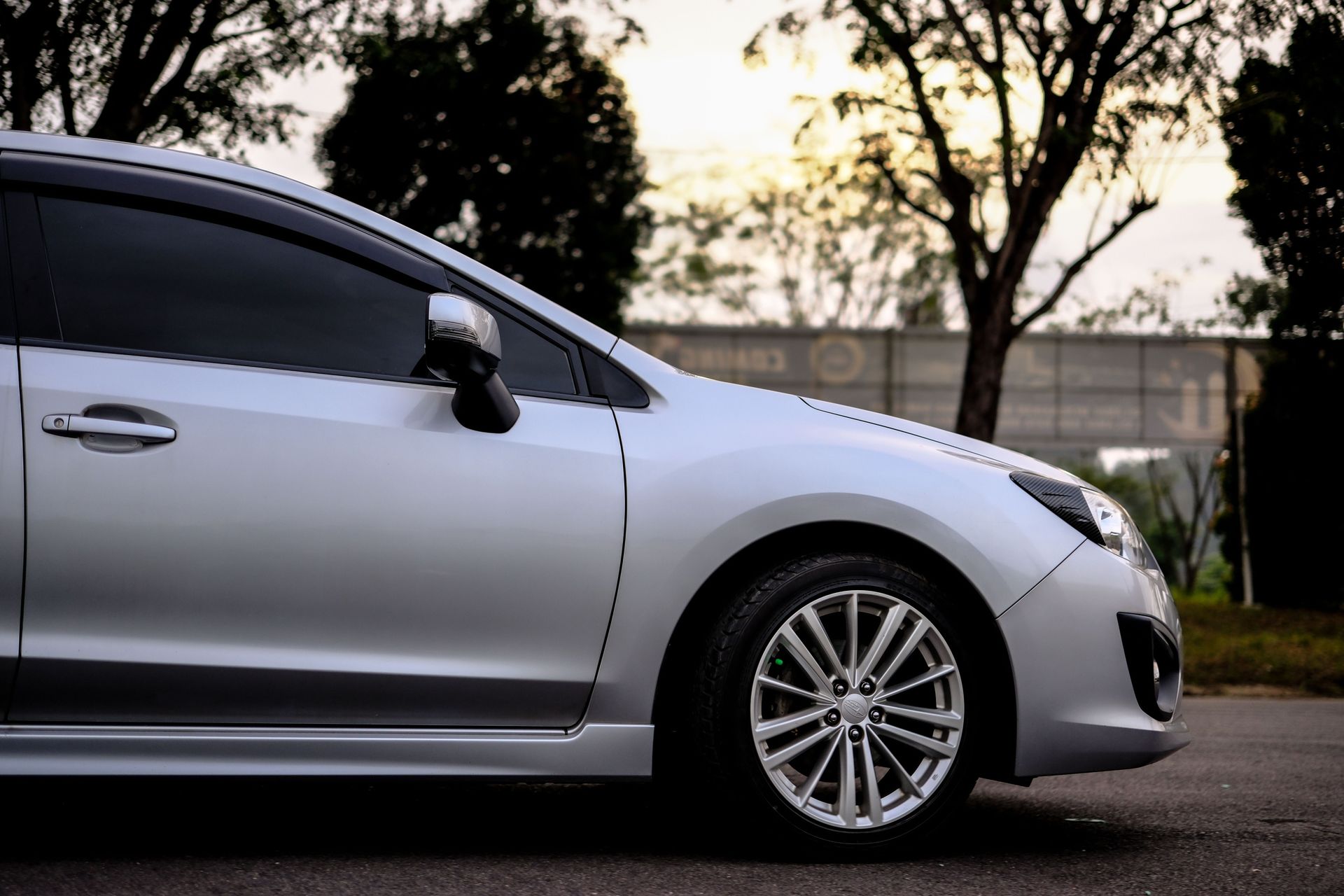 Elegant silver sports car parked outdoors at sunset, showcasing modern automotive design.